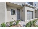 Close-up of a townhouse front entrance featuring brick walkway, gray door, garage, and window at 1213 S Station Pl # 404, Orlando, FL 32809