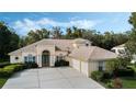 Charming home featuring a three-car garage, mature landscaping, and a light-colored exterior at 126 Seville Chase Dr, Winter Springs, FL 32708