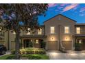 Charming two-story townhome featuring a tile roof, attached garage, and beautifully landscaped front yard at dusk at 1347 Benevolent St, Maitland, FL 32751