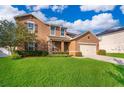 Inviting two-story home with a lush green lawn, complemented by mature landscaping and a welcoming front porch at 1920 Partin Terrace Rd, Kissimmee, FL 34744