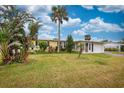 Landscaped front yard featuring a well-maintained lawn and tropical trees at 198 Benjamin Dr, Ormond Beach, FL 32176