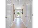 Well-lit hallway with neutral walls, tile flooring, and white doors enhancing the modern design at 2987 Brie Hammock Bnd, St Cloud, FL 34773