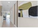 Bright hallway with neutral walls, tan tile floors, and modern artwork, leading to the dining area at 2987 Brie Hammock Bnd, St Cloud, FL 34773