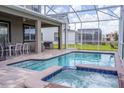 Backyard pool and spa enclosed by a screen, with an outdoor dining and seating area at 351 Ocean Course Ave, Davenport, FL 33896