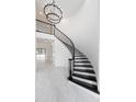 Elegant curved staircase with black iron railings and marble floors in a bright, spacious entryway at 10055 Brocksport Cir, Gotha, FL 34734