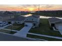 An elevated shot of a neighborhood featuring single-Gathering homes and waterfront views at sunset at 1926 Golden Beak Dr, Eagle Lake, FL 33839