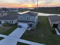 Two-story home with a two-car garage, landscaped front yard, and water view at sunset at 1926 Golden Beak Dr, Eagle Lake, FL 33839