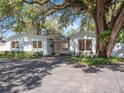 Inviting single-story home with a white exterior, well-manicured landscaping, and a large shade tree at 1932 Temple Dr, Winter Park, FL 32789