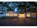 Charming single-story home with lush landscaping and a grand shade tree at twilight at 1932 Temple Dr, Winter Park, FL 32789