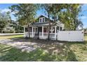 Inviting home features a gray exterior, red door, and classic front porch at 202 Division, Deland, FL 32720