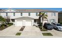 Townhome's exterior featuring a two-car garage, well-kept lawn, and modern architectural style at 360 Arbor Lakes Dr, Davenport, FL 33896