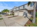 Exterior view of a townhome with a two-car garage, landscaped yard, and a palm tree at 360 Arbor Lakes Dr, Davenport, FL 33896