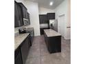 Contemporary kitchen featuring dark cabinetry, stainless steel appliances, and a large central island at 4119 Bella Isle Cir, Kissimmee, FL 34746