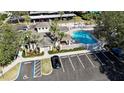 Aerial view of a community pool with palm trees, a clubhouse, parking, and ample lounge space at 583 Brantley Terrace Way # 303, Altamonte Springs, FL 32714