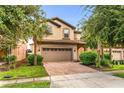 Charming home featuring brick driveway, attached garage, and mature trees enhancing its curb appeal at 8920 Rhodes St, Kissimmee, FL 34747