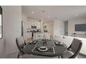 Open-concept dining area and kitchen with stainless steel appliances, granite countertops, and modern finishes at 9157 Harris Hawk Dr, Leesburg, FL 34788