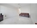 Bright living room showcasing a brown leather couch, modern ceiling fan, and clean, white tile flooring at 11901 Sandy Knoll Ct # 814, Orlando, FL 32825