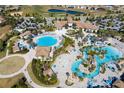 Aerial view of a resort-style pool with water slides, lounge chairs, palm trees, and a clubhouse at 1494 Moon Valley Dr, Davenport, FL 33896