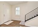 Bright foyer with a window, stylish wood floors, and an elegant staircase with a black banister at 2659 Magpie Way, Sanford, FL 32773