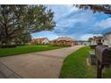 Expansive lawn and driveway lead to a beige home with a three-car garage and waterfront views at 4846 Lake Juliana Reserve Dr, Auburndale, FL 33823