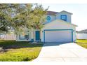 Two-story home with a tree in the yard, a two-car garage, and a blue front door at 608 Bluebill Ct, Kissimmee, FL 34759