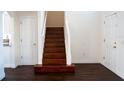 View of wooden stairs with white railing leading to upper level, adjacent to two doors at 608 Bluebill Ct, Kissimmee, FL 34759