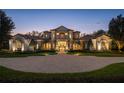 Elegant home featuring manicured landscaping, a circular driveway, and a beautiful stone and stucco facade at twilight at 6126 Kirkstone Ln, Windermere, FL 34786