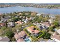 Aerial view of a landscaped home with a pool, screened lanai, and lake view at 8424 Lake Burden Cir, Windermere, FL 34786