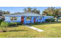 Inviting single-story home featuring a colorful exterior, red doors, and a lush green lawn at 200 Dr Martin Luther King Jr Se St, Fort Meade, FL 33841