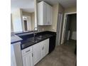 Well-lit kitchen with stainless steel sink, black appliances, white cabinets, and black granite counters at 2516 Grassy Point Dr # 206, Lake Mary, FL 32746