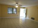 A bright living room with neutral walls, tile flooring, ceiling fan, and a front door leading to the outside at 4790 Point Look Out Rd, Orlando, FL 32808