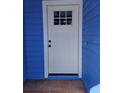 Close-up of a white front door framed by bright blue siding and a small landing area at 703 Pine Shores Cir, New Smyrna Beach, FL 32168