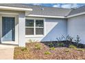 A close-up view of the entry door, window, and landscape of the front exterior of the home at 7139 Se 122Nd Ln, Belleview, FL 34420