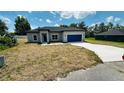 Charming single-story home showcasing a well-manicured lawn and a blue two-car garage at 11 Spruce Ln, Ocala, FL 34472