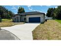Charming single-story home showcasing a well-manicured lawn and a blue two-car garage at 11 Spruce Ln, Ocala, FL 34472