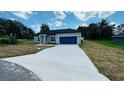 Charming single-story home showcasing a well-manicured lawn and a blue two-car garage at 11 Spruce Ln, Ocala, FL 34472