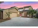 Inviting tan two-story home with attached garage, mature landscaping, and brick accents at sunset at 229 Springside Rd, Longwood, FL 32779