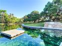 Beautiful view of the crystal clear pond with mature landscaping and a dock at 229 Springside Rd, Longwood, FL 32779