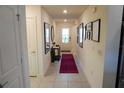 Bright hallway with neutral tile flooring, decorative wall art, and access to various rooms at 2305 Biscotto Cir, Davenport, FL 33897