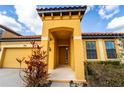 Inviting entrance to a yellow house with a red tile roof, enhancing curb appeal and highlighting architectural details at 2610 Rosemont Cir, Davenport, FL 33837