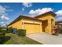 A view of the side of the house and garage showcasing the home's sunny yellow exterior and tile roof at 2610 Rosemont Cir, Davenport, FL 33837