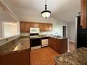 Functional kitchen featuring wooden cabinets, granite countertops, and modern appliances at 6725 Sawmill Blvd, Ocoee, FL 34761