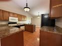 Functional kitchen featuring wooden cabinets, granite countertops, and modern appliances at 6725 Sawmill Blvd, Ocoee, FL 34761