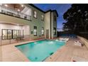 A backyard pool at dusk, featuring submerged loungers, an outdoor shower, and patio with a ping pong table at 7465 Gathering Loop, Reunion, FL 34747