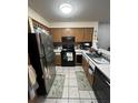 Compact kitchen with stainless steel refrigerator, black appliances, and tiled floor at 13941 Fairway Island Dr # 733, Orlando, FL 32837