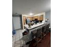 Open kitchen view to the bar with barstool seating, stainless fridge, and tile flooring at 13941 Fairway Island Dr # 733, Orlando, FL 32837