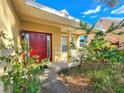 Covered front porch with bright red front door framed by lush tropical foliage at 4331 Willowcrest Ct, Orlando, FL 32826