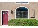 Close up of a townhome exterior featuring a red door, arched window, and green hedges at 606 Casa Park I Court, Winter Springs, FL 32708