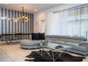 Stylish living room featuring a modern sectional, unique coffee table, and striped accent wall at 8948 Adriatico Ln, Kissimmee, FL 34747