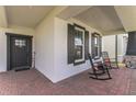 Inviting front porch featuring brick flooring, rocking chairs, and stylish exterior shutters at 13819 Lanyard Way, Winter Garden, FL 34787